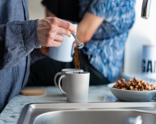 Person taking a quick stretching break in the kitchen while making coffee