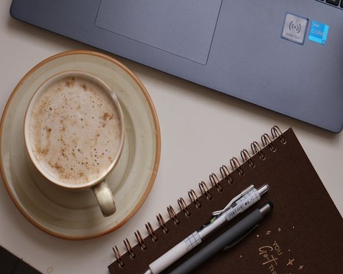 A neat desk setup with a notebook, pen, and a cup of tea ready for study